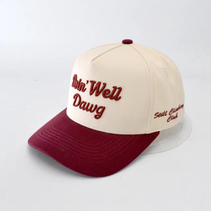 Beige and maroon cap with embroidered text on a light gray background